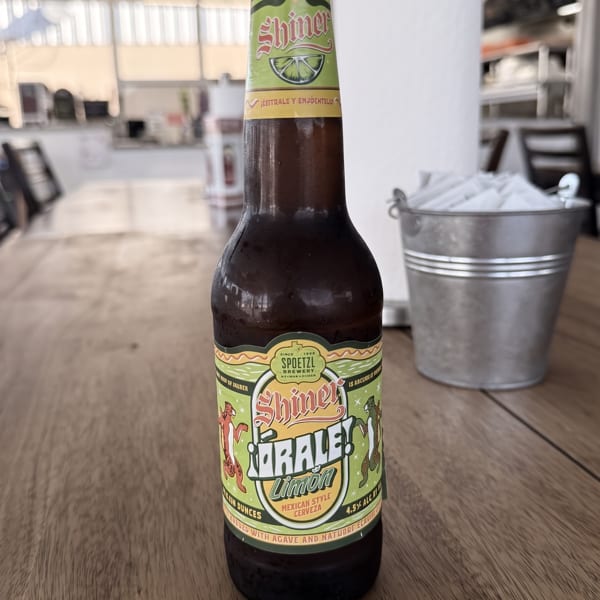Cold Shiner Orale! Limón Mexican Style Cerveza bottle on a wooden table with napkins.