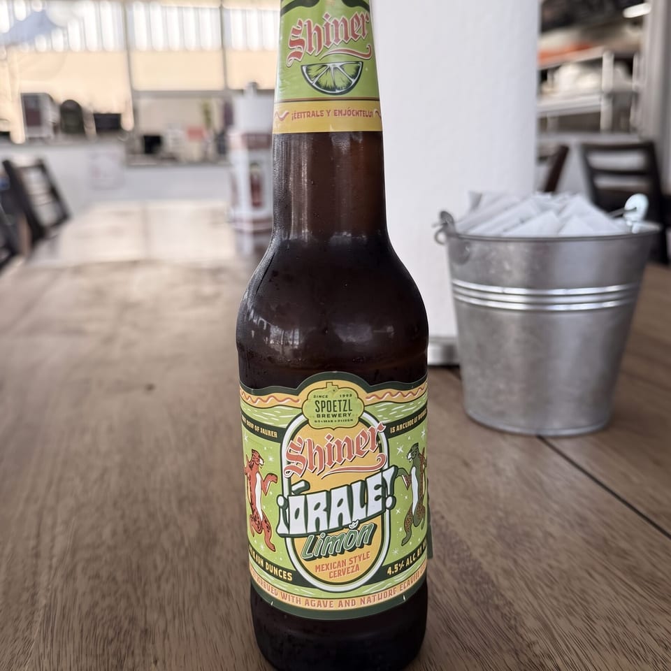 Cold Shiner Orale! Limón Mexican Style Cerveza bottle on a wooden table with napkins.